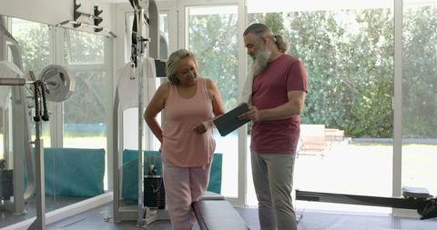Senior couple discussing fitness goals in home gym with tablet