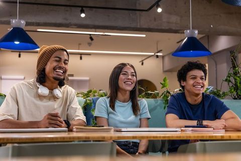 Young diverse team laughing and collaborating at modern coworking table with greenery