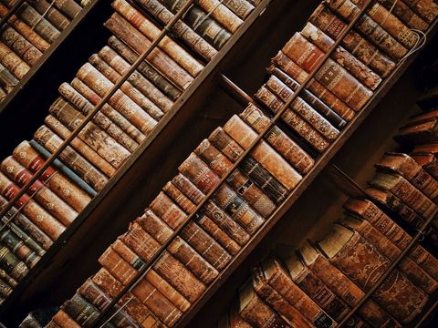 Vintage Leather-Bound Books Stacked in Wooden Shelves