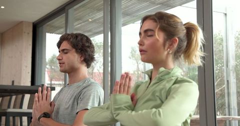 Friends Practicing Yoga Prayer Pose by Large Windows