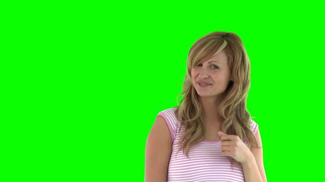 Model is standing against a solid green background, which makes the video ideal for chroma key projects. She is smiling and appearing playful, adding a touch of personality. Useful for advertisements, promotional materials, fashion blogs, or any content requiring vibrant and dynamic visuals.