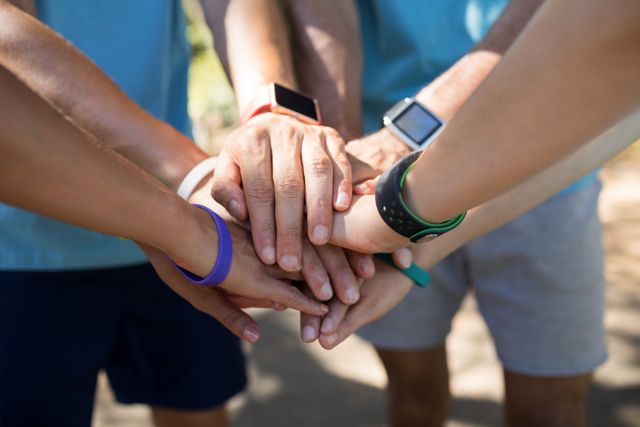 This image shows a close-up of marathon athletes forming a hands stack, symbolizing teamwork and unity. Ideal for use in sports-related content, motivational materials, fitness blogs, and promotional materials for team-building events.