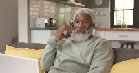 Senior man discussing over phone in modern kitchen environment