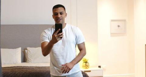 Young Man Taking Selfie in Modern Bedroom Setting