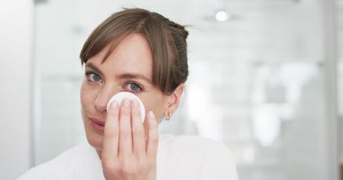 Woman relaxed cleansing skin with cotton pad