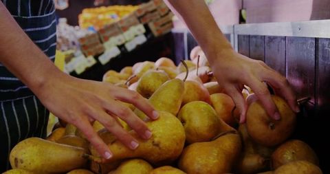 Vendor Arranging Fresh Pears on Market Display Stand