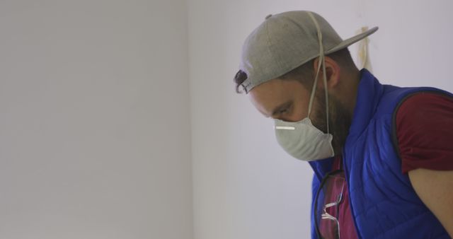 Man Wearing Cap and Protective Mask Painting Wall Indoors - Download Free Stock Images Pikwizard.com