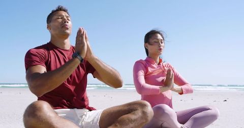 Multicultural Couple Meditating on Sunny Beach Practicing Mindful Breathing and Yoga