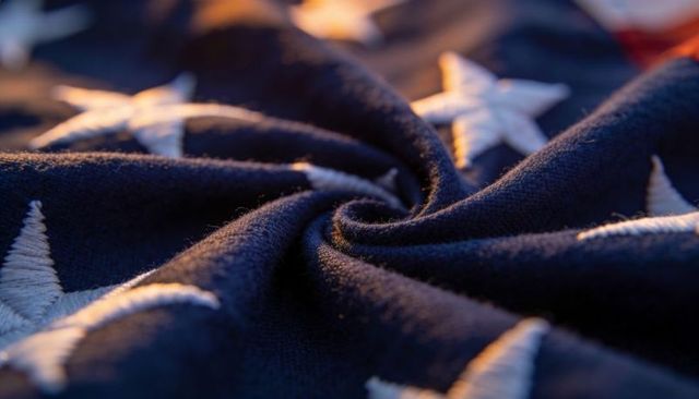 Macro spiral of navy embroidered stars on twisted fabric with warm side light