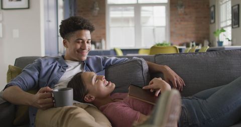 Biracial Couple Relaxing on Sofa with Coffee at Home
