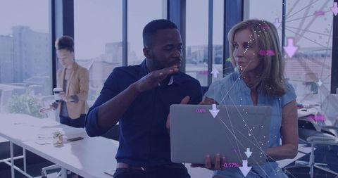 Colleagues analyzing digital data overlays on laptop in open-plan office with urban skyline