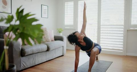 African american woman practicing low lunge twist in bright living room yoga session