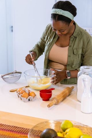 African american woman mixing batter at kitchen island whipping ingredients for baking