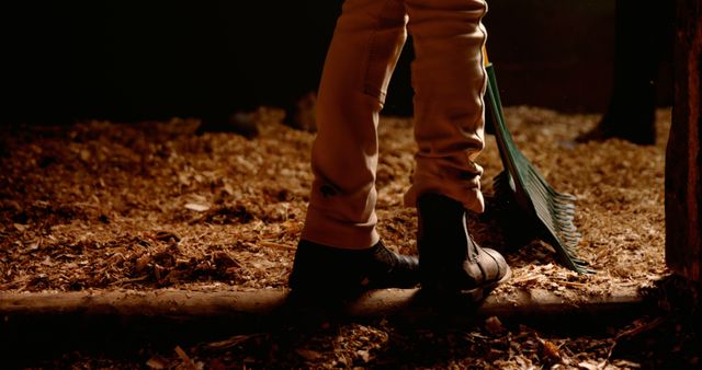 Legs of woman cleaning horse's stable with shovel with copy space. Horse, horse riding and dressage concept, unaltered.