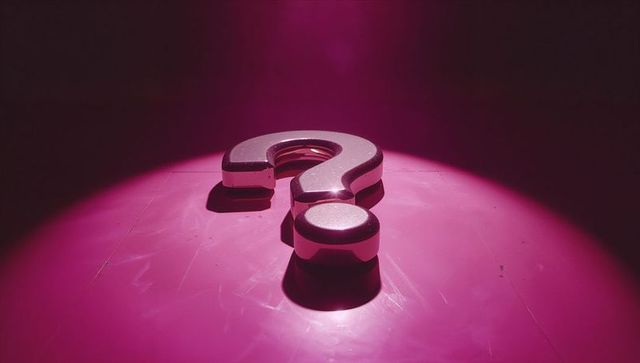 Metallic 3d question mark on glossy pink floor with spotlight effect