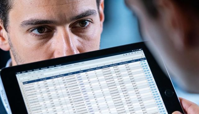 Focused man studying spreadsheet on tablet in business meeting closeup showing data