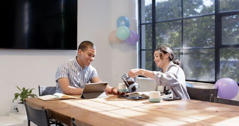 Co-workers enjoying coffee break with laptops and business discussions