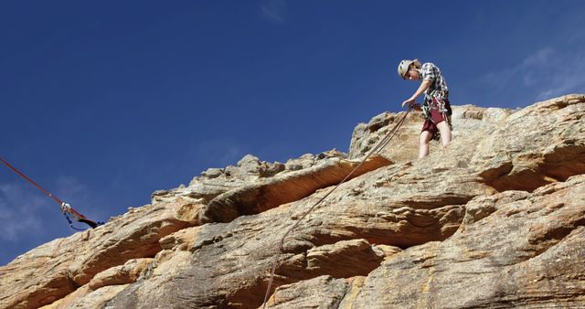 Rock climber abseiling on rocky cliff under sunny sky - Download Free Stock Images Pikwizard.com