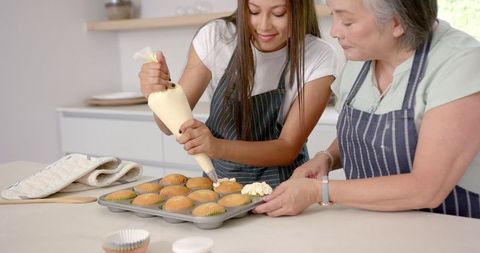 Girl and Grandmother Decorating Cupcakes in Home Kitchen