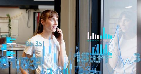 Professional woman talking on smartphone with data visualization and window reflection