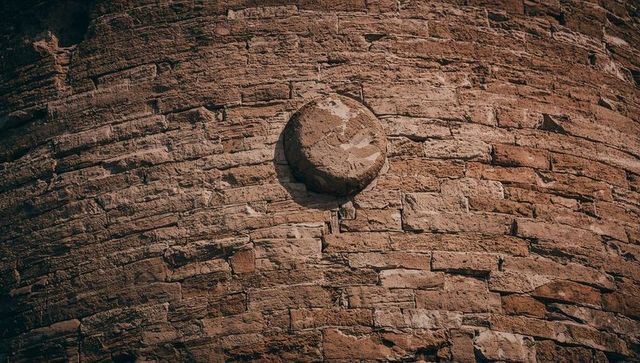 Featuring weathered circular masonry boss on curved brick tower with sunlit patina
