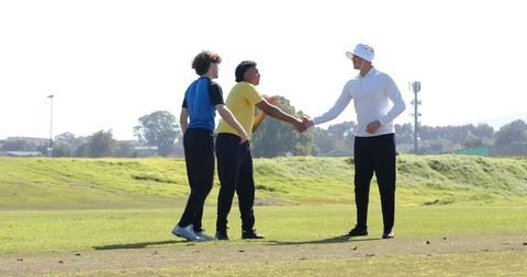 Coach and Players Shaking Hands on Green Field Promoting Team Spirit