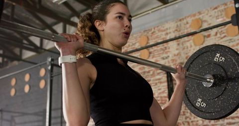Determined Woman Lifting Barbell in Industrial Gym