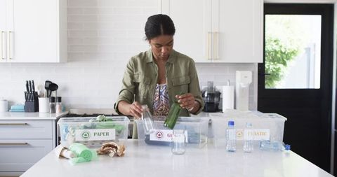 Young woman sorts recyclables in kitchen sustainability at home