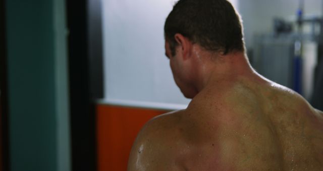 Detailed shot of a muscular man with a sweaty back, highlighting effort after an intense workout session. Beneficial for fitness and health-related content, strength training programs, gym promotions, and motivational purposes. Perfect for use in fitness magazines, training guides, and health blogs.