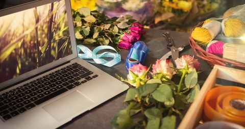 Laptop Displaying Nature Amidst Flower Arrangement Tools