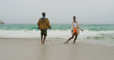Joyful Couple Embracing Beach Waves in Relaxed Atmosphere