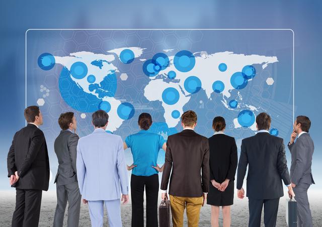 Digital composition of team of business executives looking at world map