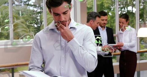 Businessman reviewing documents and pondering sustainable office strategy with team