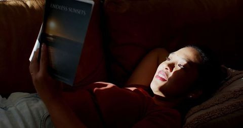 Woman relaxing on couch reading endless sunsets magazine