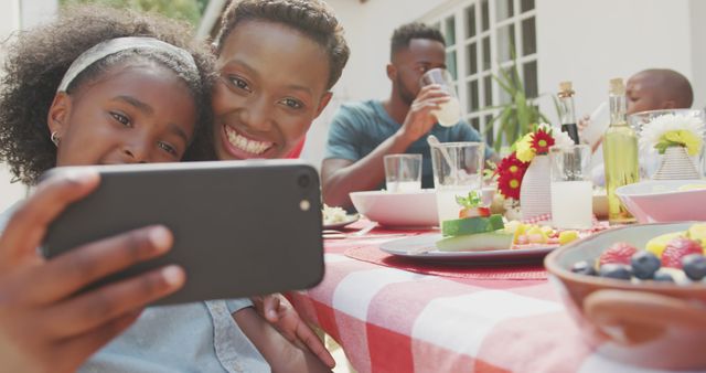 Happy caucasian family sitting at table in garden, taking selfie. Lifestyle, domestic life, communication, family, and togetherness.