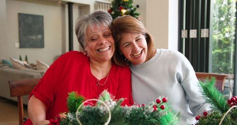 Two Women Smiling Together at Home Dining Table during Holidays