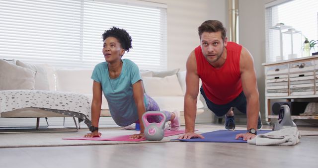 Image of happy diverse couple training together at home, doing plank. Love, relationship and spending quality time together at home.