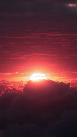 Vertical sunrise over cloudscape creating red and pink layered bands of dramatic light