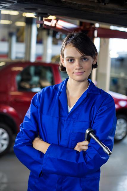 Portrait of female mechanic standing with arms crossed in repair garage
