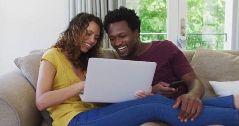Cheerful Couple Enjoying Leisure Time with Laptop at Home