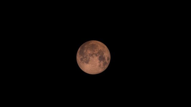 The Super Blood Moon glowing in a nighttime sky. Ideal for articles about lunar eclipses, space phenomena, and night photography. This dramatic image highlights the orange-red hue caused by Earth's shadow during the eclipsing phase. Perfect for educational content on lunar cycles.