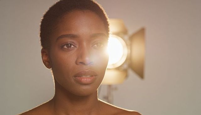 Gazing forward under cinematic backlight, short natural hair, rimlit beauty headshot