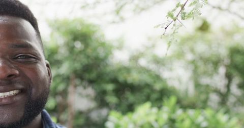 Joyful african american man smiling in green outdoors