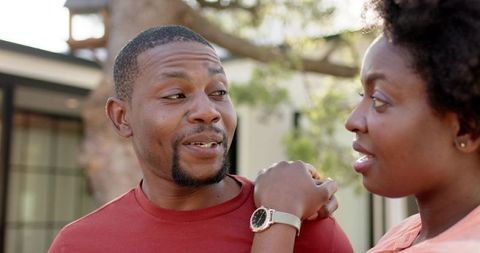 African american couple chatting in yard while woman shows watch casual suburban moment