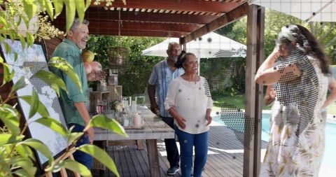 Multigenerational Friends Greeting on Backyard Pergola Deck by Pool at Casual Garden Party