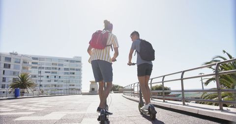 Gay Couple Enjoying Scooters by Oceanfront Promenade