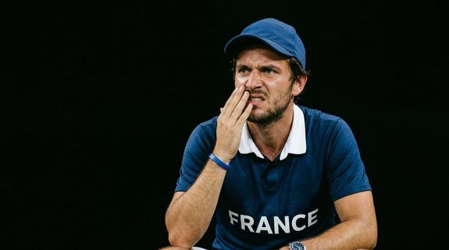 Frustrated france athlete pressing hand to cheek on sideline showing tension and focus