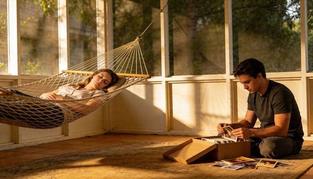Couple relaxing in sunlit screened porch with hammock and sorting vintage prints