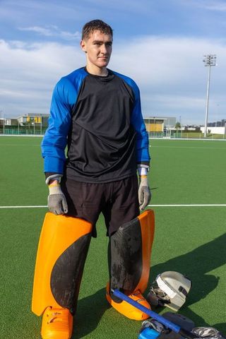 Teenage field hockey goalkeeper ready for practice on turf