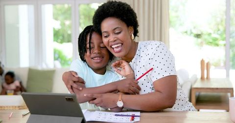 Happy Mother Helping Son with Homework Using Tablet at Home